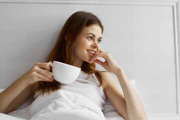 woman lies in bed with a cup of coffee relaxation morning fun