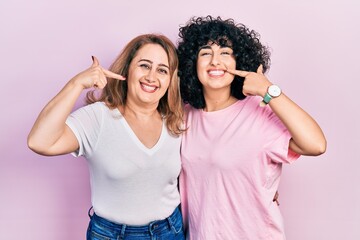 Middle east mother and daughter wearing casual clothes smiling cheerful showing and pointing with fingers teeth and mouth. dental health concept.