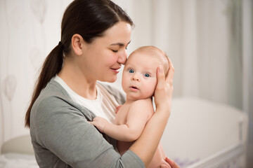 Close up portrait of beautiful young mother girl kissing her newborn baby