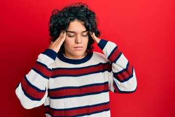 Obraz na płótnie Canvas Young hispanic woman with curly hair wearing casual winter sweater with hand on head, headache because stress. suffering migraine.