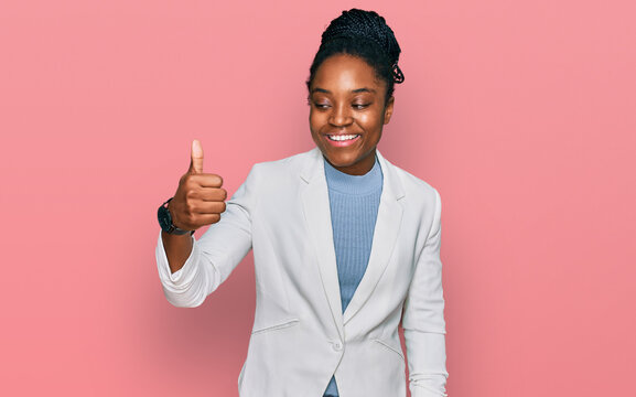 Young african american woman wearing business clothes looking proud, smiling doing thumbs up gesture to the side