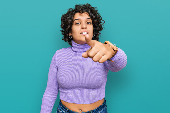 Young hispanic woman with curly hair wearing casual clothes pointing displeased and frustrated to the camera, angry and furious with you