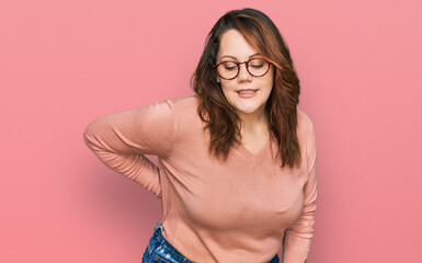 Young plus size woman wearing casual clothes and glasses suffering of backache, touching back with hand, muscular pain