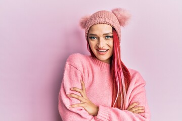 Young caucasian woman wearing wool sweater and winter hat happy face smiling with crossed arms looking at the camera. positive person.