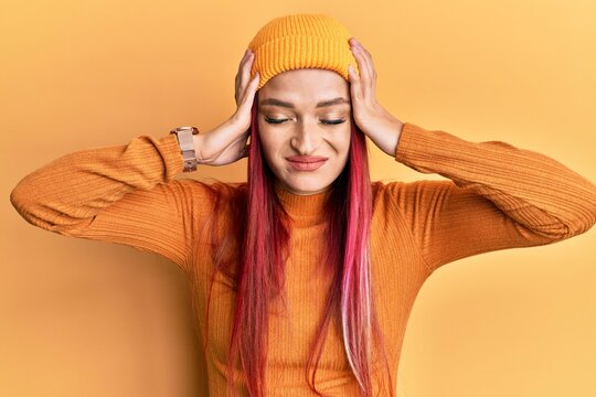 Young caucasian woman wearing wool cap suffering from headache desperate and stressed because pain and migraine. hands on head.