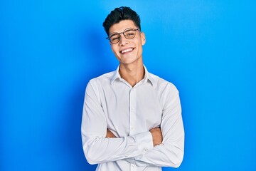 Young hispanic man wearing casual clothes and glasses happy face smiling with crossed arms looking at the camera. positive person.