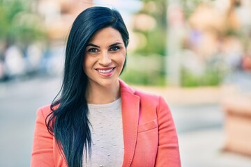 Fototapeta premium Young beautiful businesswoman smiling happy standing at the city.