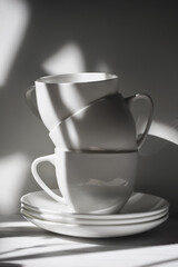 Three porcelain cups and saucers in the shade of a tree in black and white - 435138927