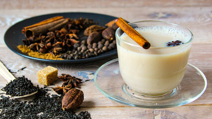 Traditional indian drink - masala tea with spices wooden background. Close up popular Indian or...
