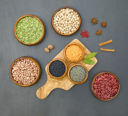 Flat lay of various sources of vegetable protein and spices: beans, lentils, peas, chickpeas, mung bean in bowls. Black background. Culinary top view, copy space.