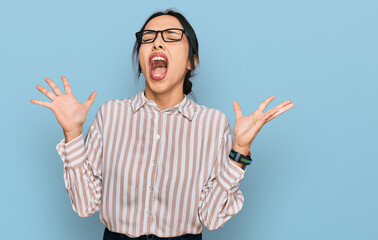 Young hispanic girl wearing casual clothes and glasses celebrating mad and crazy for success with...