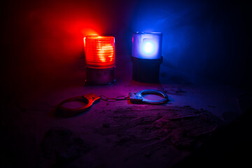 Police raid at night and you are under arrest concept. Silhouette of handcuffs with police car on...