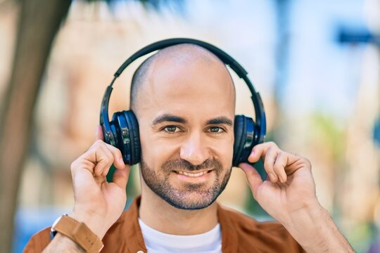 Young hispanic bald man smiling happy using headphones at the city