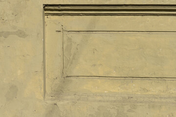 Wall with cement plaster and rustic moldings painted in light brown