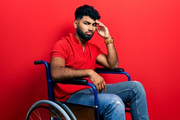 Arab man with beard sitting on wheelchair worried and stressed about a problem with hand on forehead, nervous and anxious for crisis