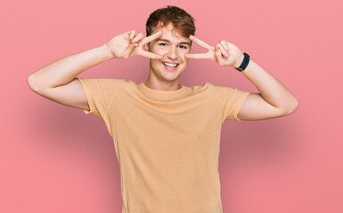 Young caucasian man wearing casual clothes doing peace symbol with fingers over face, smiling cheerful showing victory