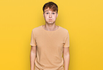 Young caucasian man wearing casual clothes puffing cheeks with funny face. mouth inflated with air, crazy expression.