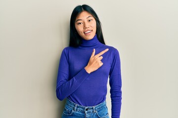 Young chinese woman wearing casual clothes smiling cheerful pointing with hand and finger up to the side