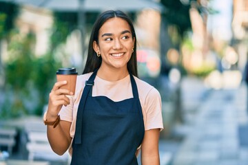Young latin barista girl smiling happy holding take away coffee at the cafe shop