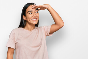 Fototapeta premium Young asian woman wearing casual clothes very happy and smiling looking far away with hand over head. searching concept.