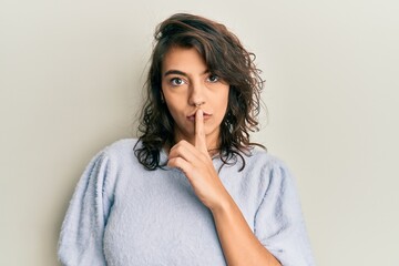 Young hispanic woman wearing casual winter sweater asking to be quiet with finger on lips. silence and secret concept.