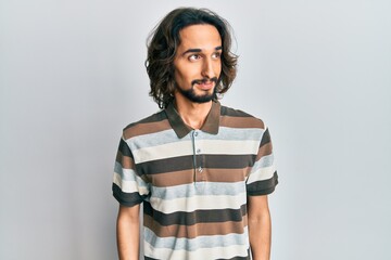 Young hispanic man wearing casual clothes looking to side, relax profile pose with natural face and confident smile.