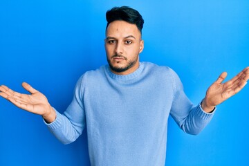 Young arab man wearing casual clothes clueless and confused with open arms, no idea and doubtful face.