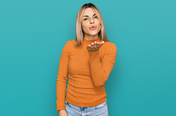 Young caucasian woman wearing casual clothes looking at the camera blowing a kiss with hand on air...