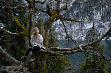 Girl sits on a tree and meditates near lake Ritsa in Abkhazia