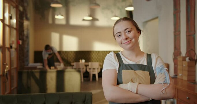 Happy young waitress taking off mask