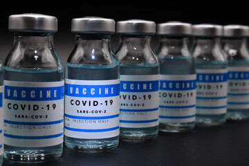 Covid-19 vaccine vials lined up on a black background