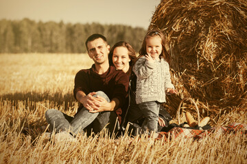 Naklejka na ściany i meble Happy young family with two year old baby girl next to hay bales