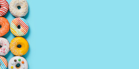 Delicious glazed donuts on blue background. Vertical flat lay - set of different colorful donuts or...
