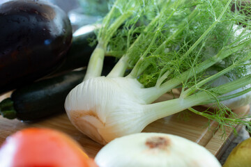 A view of several produce on a wood cutting board, featuring a fennel bulb.