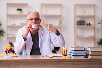 Old male dentist teacher sitting in the classroom