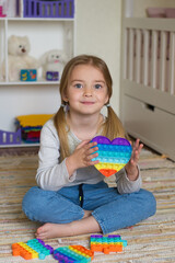 children's popular pop it toy, baby girl holding anti-stress toy in her hands