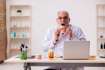 Old male dentist working in the clinic