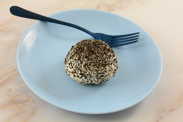 Coconut and coffee snowball cake on blue dessert plate with blue fork