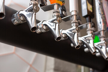 A closeup view of several spout portion of beer taps, in a restaurant, bar or brewery setting.