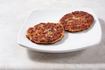 A view of two sausage patties on a plate.