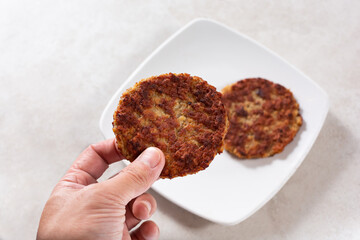 A view of a hand holding a breakfast sausage patty.