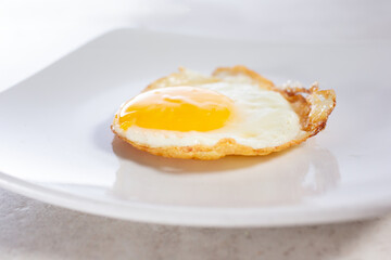 A closeup view of a plate of one fried egg.