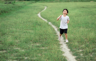 happy little Asian boy run on the field