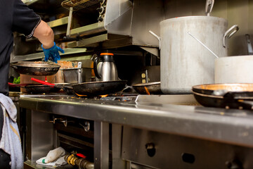 A low angle view of a restaurant kitchen cooking area, featuring stockpots, grilled food, clutter...