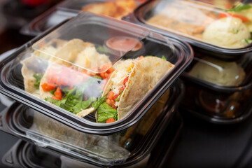A view of several entrees prepared inside to-go plastic containers, ready for take out orders, in a...