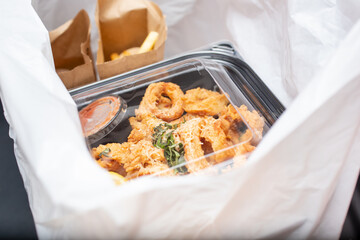 A view inside a plastic bag, featuring to-go containers of prepared food orders, in a restaurant setting.