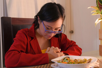 Young woman with Down syndrome praying before consuming her food, trisomy 21, red blouse, prayer...