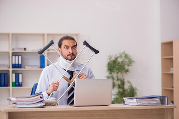 Young man employee after accident working in the office