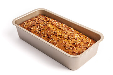A loaf of banana bread with pecan pieces baked in fresh from the oven in its baking pan isolated on white

