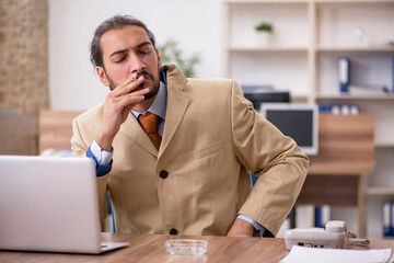 Ill cigarette addicted male employee working in the office